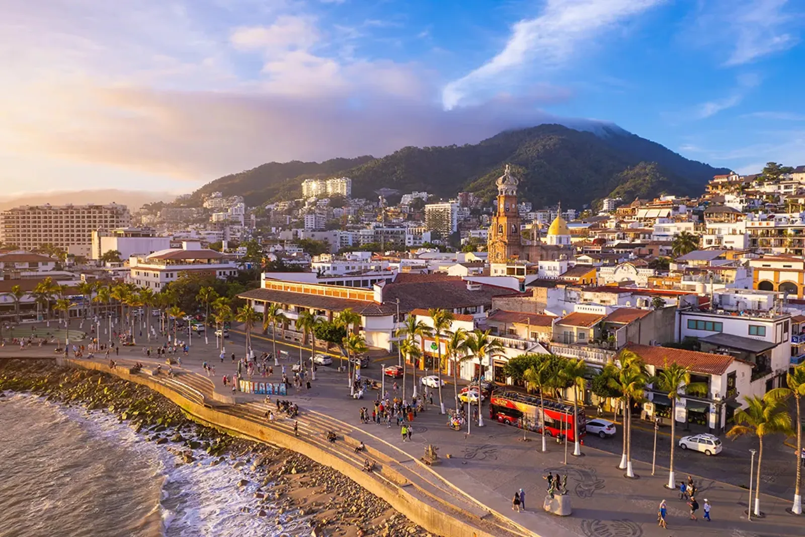 Puerto Vallarta’s Malecón and the Our Lady of Guadalupe church tower at sunset, with the old town rising to the hills