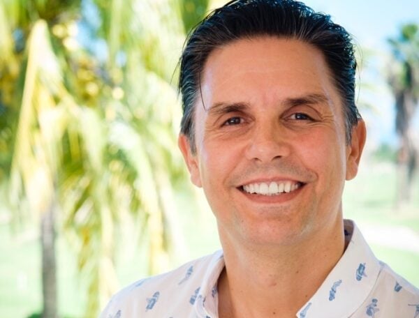 Portrait of Oliver Weickardt, smiling beneath palm trees.