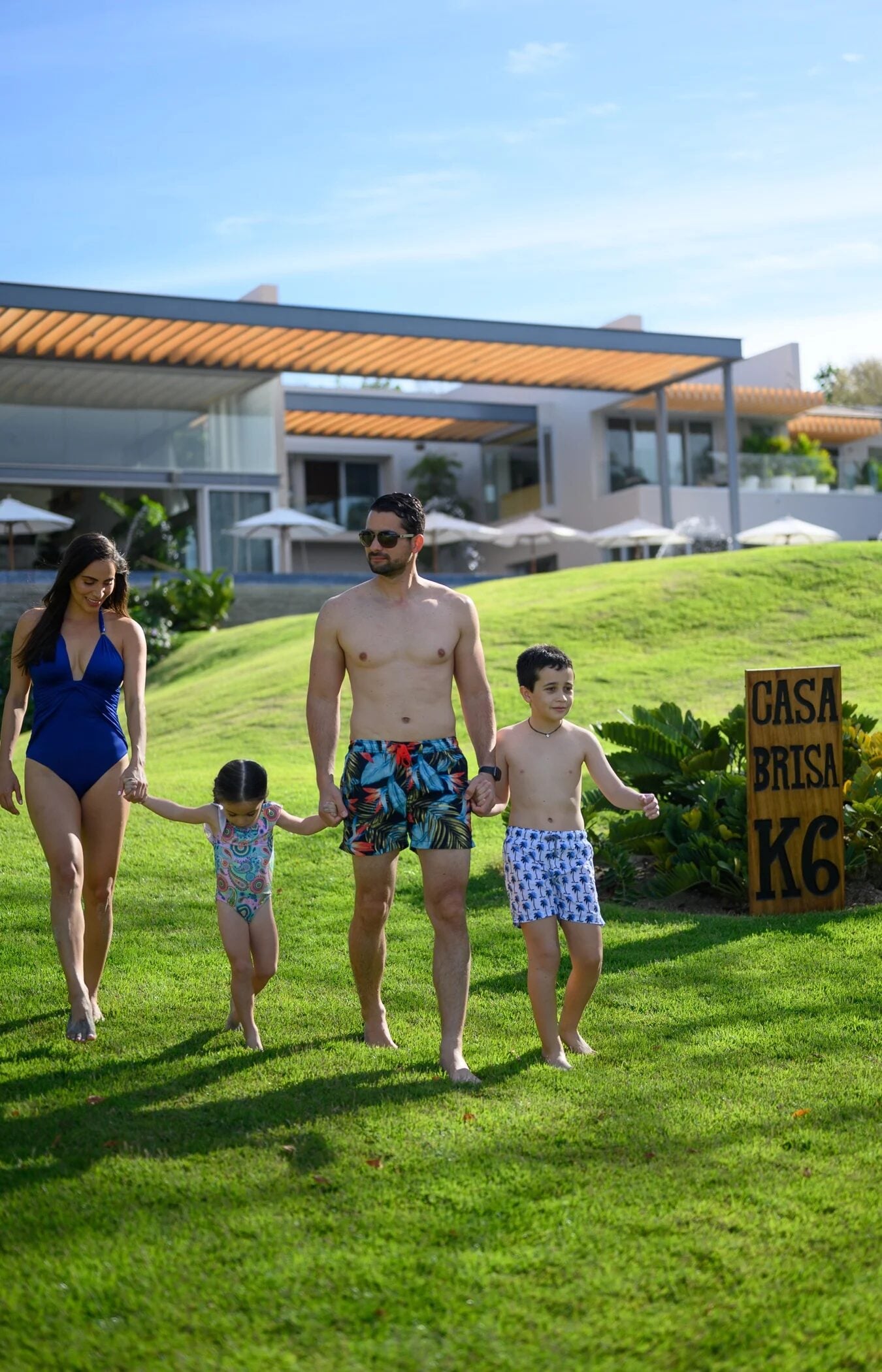 A family of four walks hand in hand across the lawn at Casa Brisa in Punta Mita.