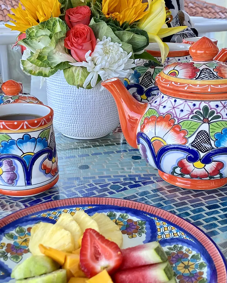 A breakfast table set with hand-painted Talavera ceramics, fresh fruit and flowers.