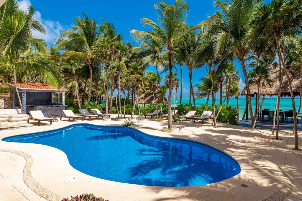 Casa Yardena swimming pool bordered by palms and ocean-facing loungers — Tulum, Mexico