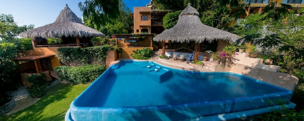 Villa Rigoletti swimming pool with tiled steps and two thatched pavilions — Ixtapa Zihuatanejo, Mexico