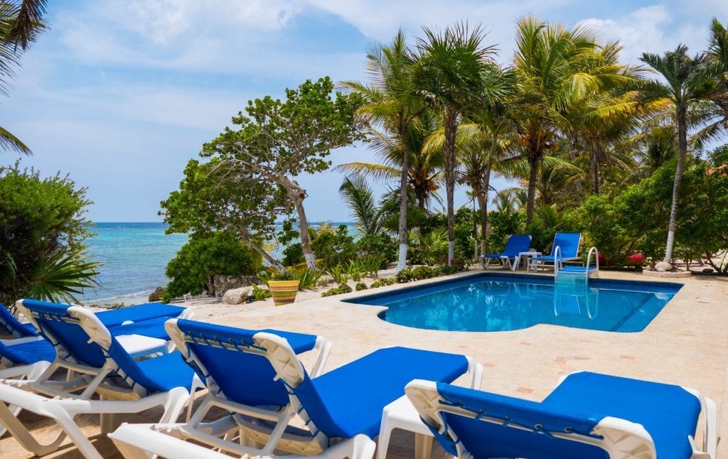 Villa Ka Kuxta row of blue loungers on the pool deck with ocean view — Akumal, Mexico