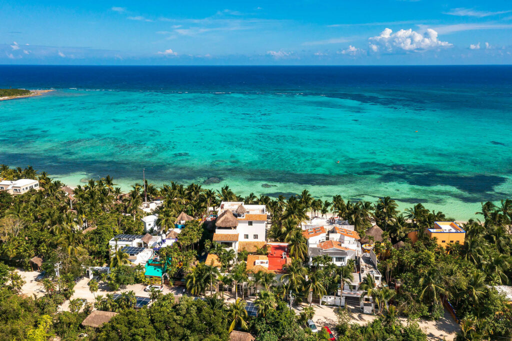 The Soliman Bay shoreline from the air, houses set back behind the palms and the reef offshore