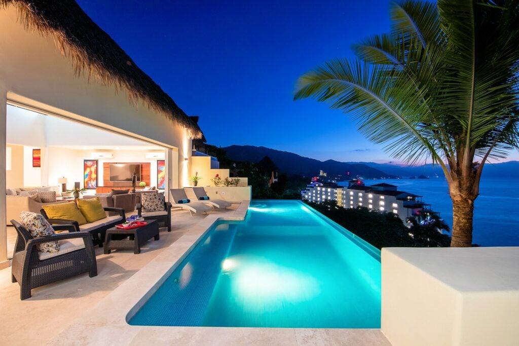 Casa Suhana illuminated pool beside the open living area at twilight — Puerto Vallarta, Mexico