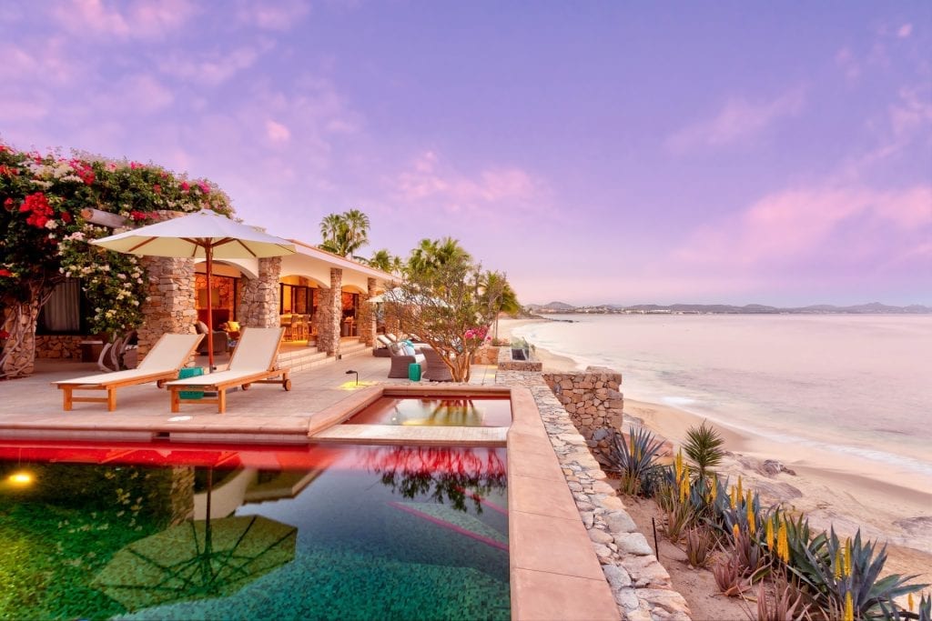 Casa Mañana pool and terrace above the beach beneath a pink sky — Los Cabos, Mexico