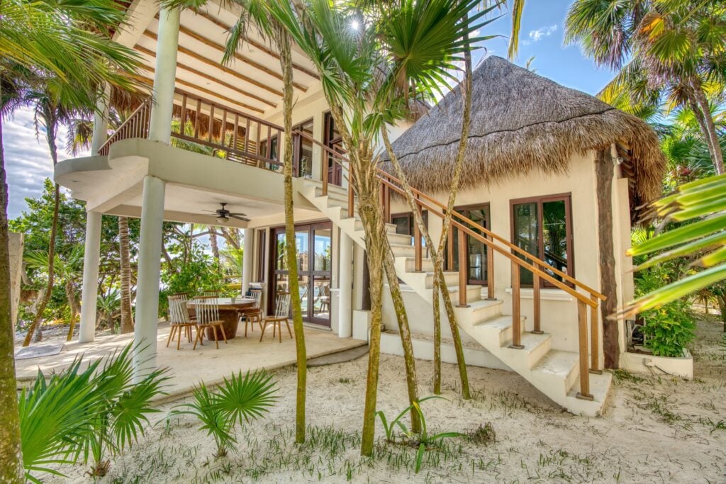 Casa Corazon Uno two-story bungalow exterior with staircase palapa roof and palms — Soliman Bay Tulum