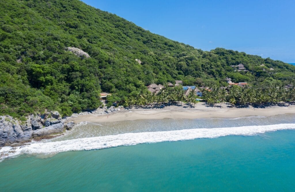 Casa Alima aerial view of a rocky beach edge below a green hillside — San Juan de Alima, Mexico