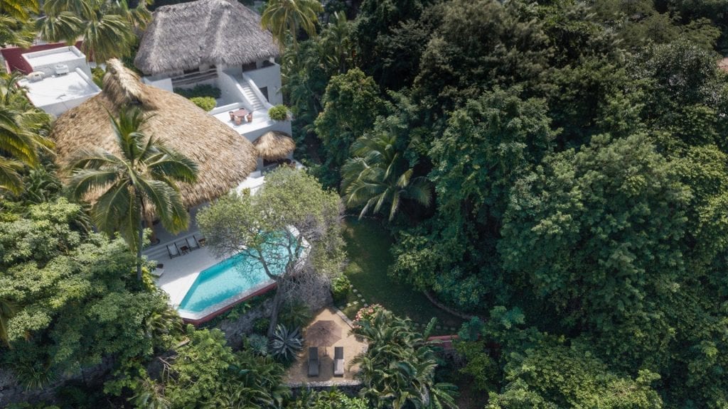 Casa del Sol aerial view of the thatched-roof villa and pool amid greenery — Ixtapa Zihuatanejo, Mexico