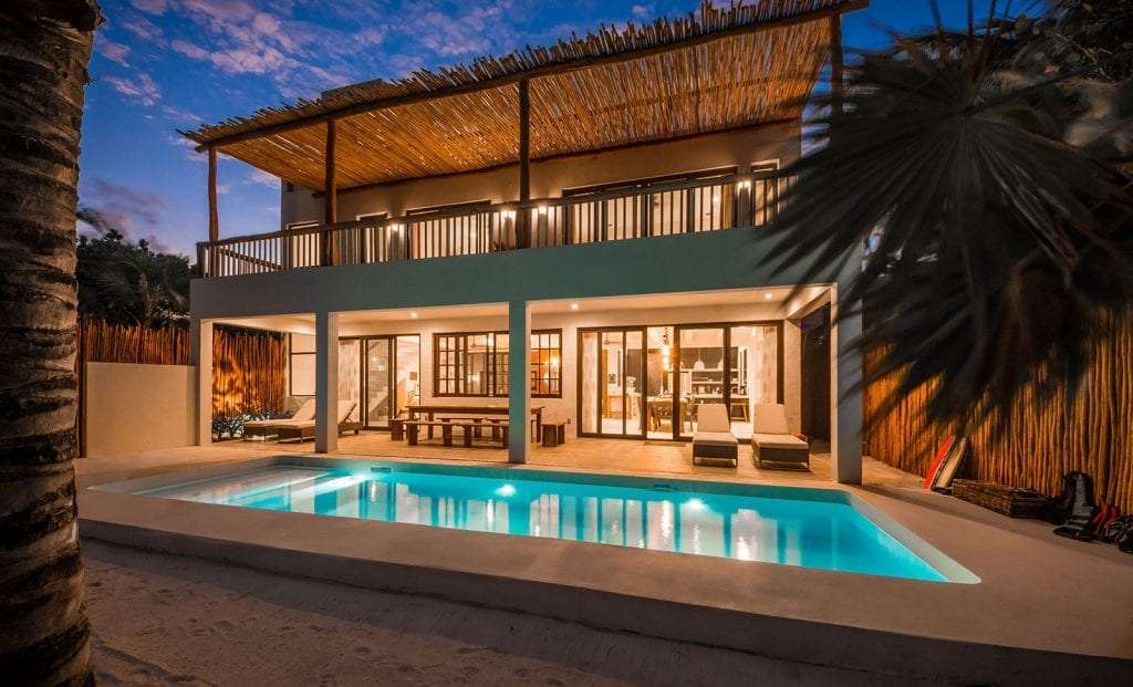 Kevali Beach House two-story exterior with a lit pool and terrace at dusk — Tulum, Mexico