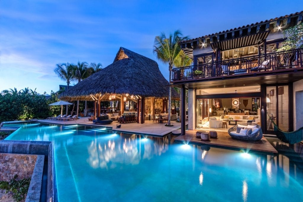 Casa Koko illuminated pool beside a palapa and two-story wing at dusk — Punta Mita Nayarit, Mexico