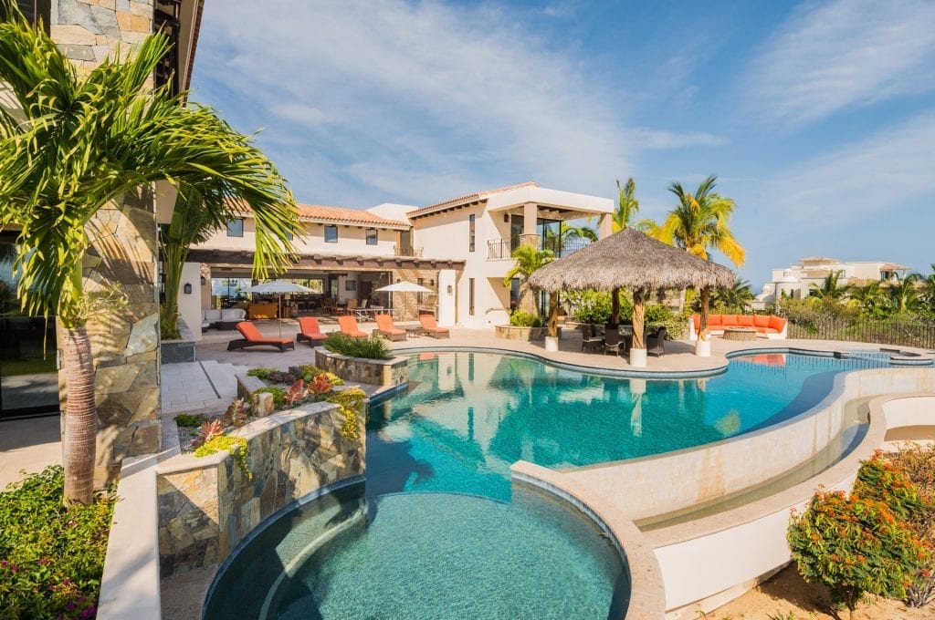 Casa de Sueños elevated view of the villa, rounded pool sections and thatched dining pavilion — Los Cabos, Mexico