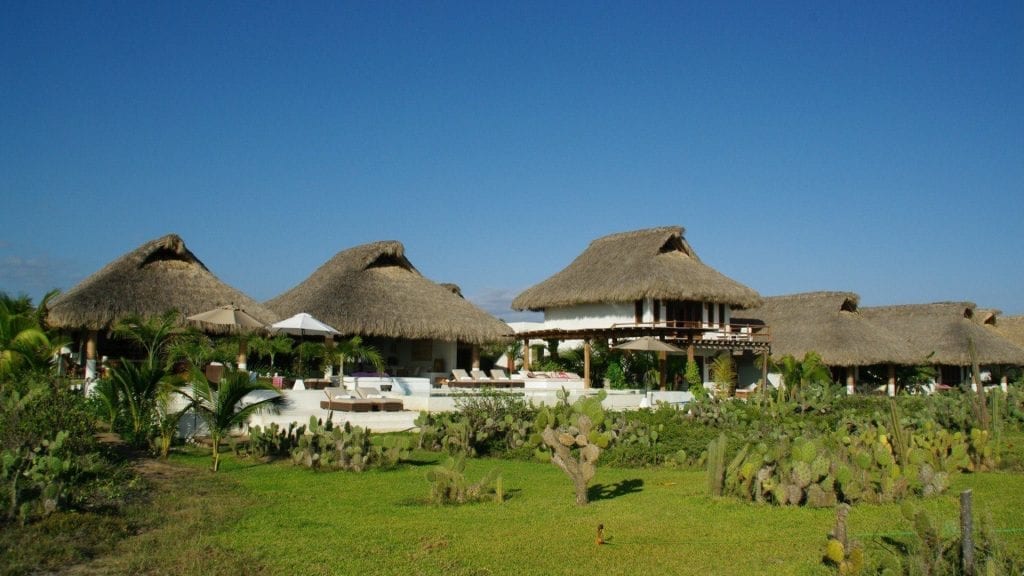 Casa Macaria three thatch roofs on the green above the cactus — Puerto Escondido, Mexico