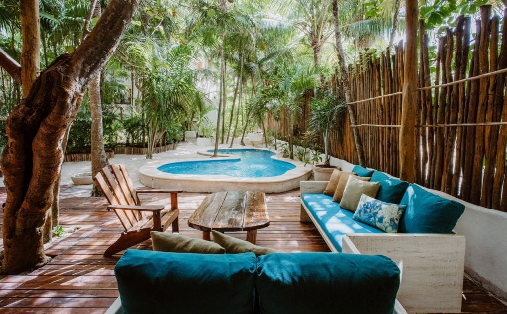 Casa Mandala deck lounge with turquoise sofas and a wood table by the pool — Tulum, Mexico