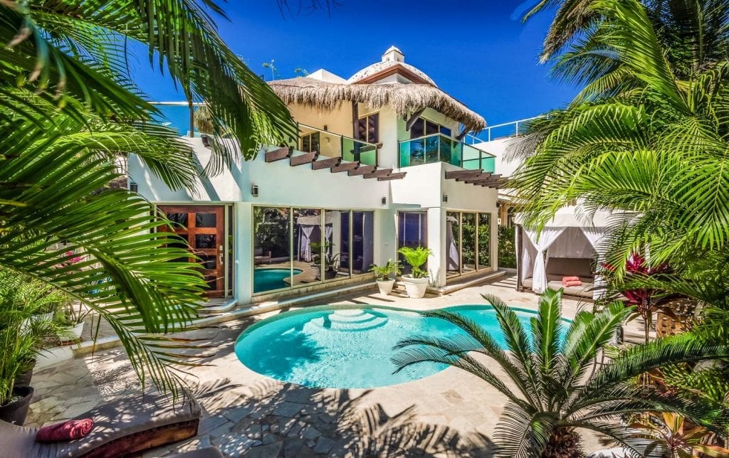 Casa Nikki villa exterior framed by palms with pool and cabana — Playa del Carmen, Mexico
