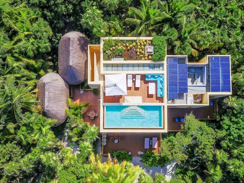 Hacienda Chekul overhead view of the pool, solar panels and thatched roofs among trees — Tulum, Mexico