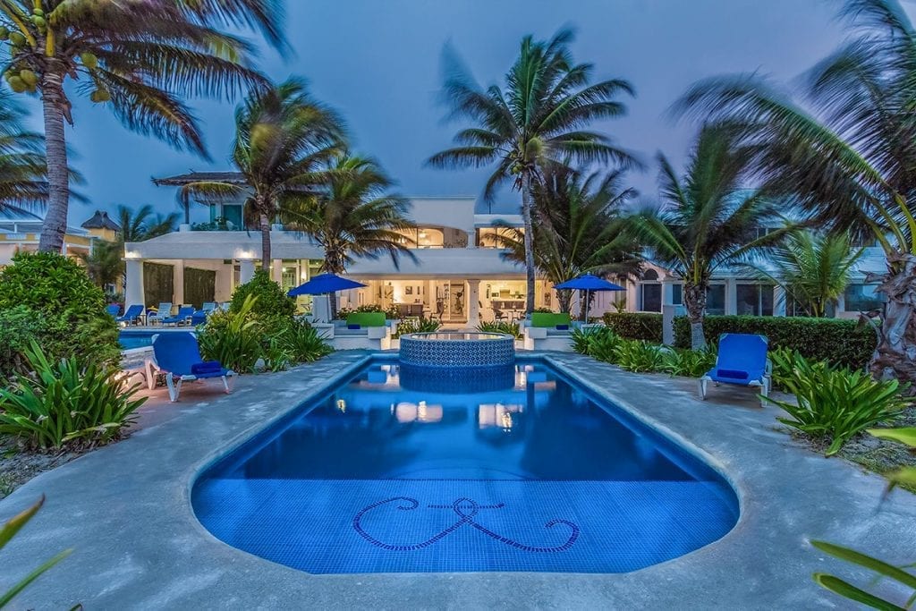 Hacienda del Secreto swimming pool at dusk framed by palms and loungers — Playa del Carmen, Mexico