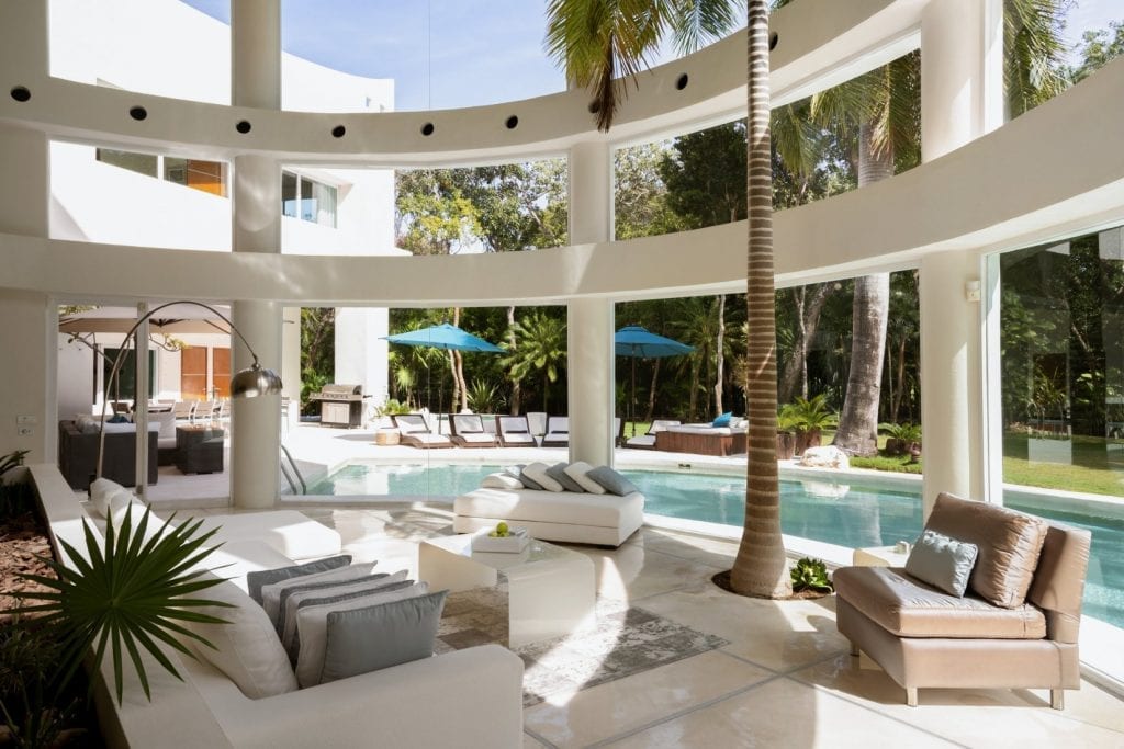 Villa Aqua glass rotunda sitting area with palm and turquoise pool umbrellas beyond — Playa del Carmen, Mexico