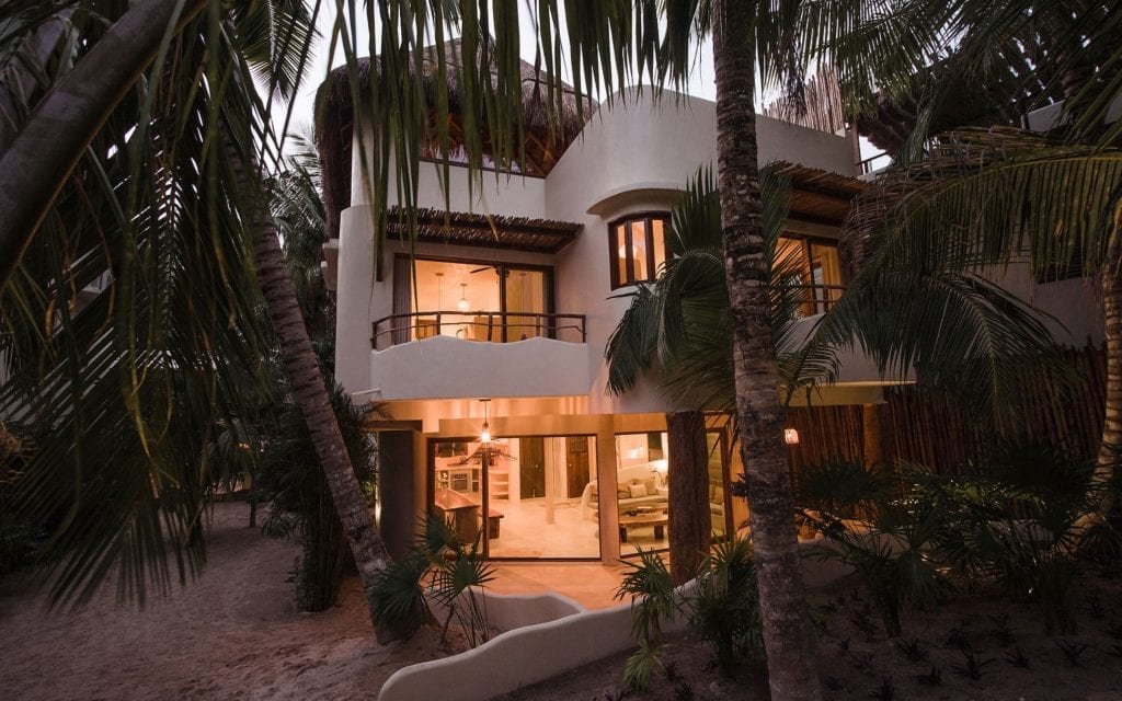 Zorba Cuatro lit from within at dusk among the palms, Tulum villa rental