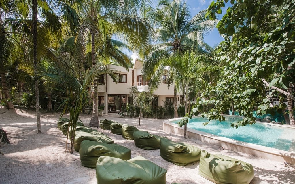 The communal pool at Zorba Dos with green loungers set out under the palms, Tulum
