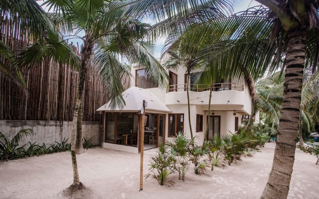 Zorba Uno garden facade with glass-walled room and upper balcony — Tulum, Mexico