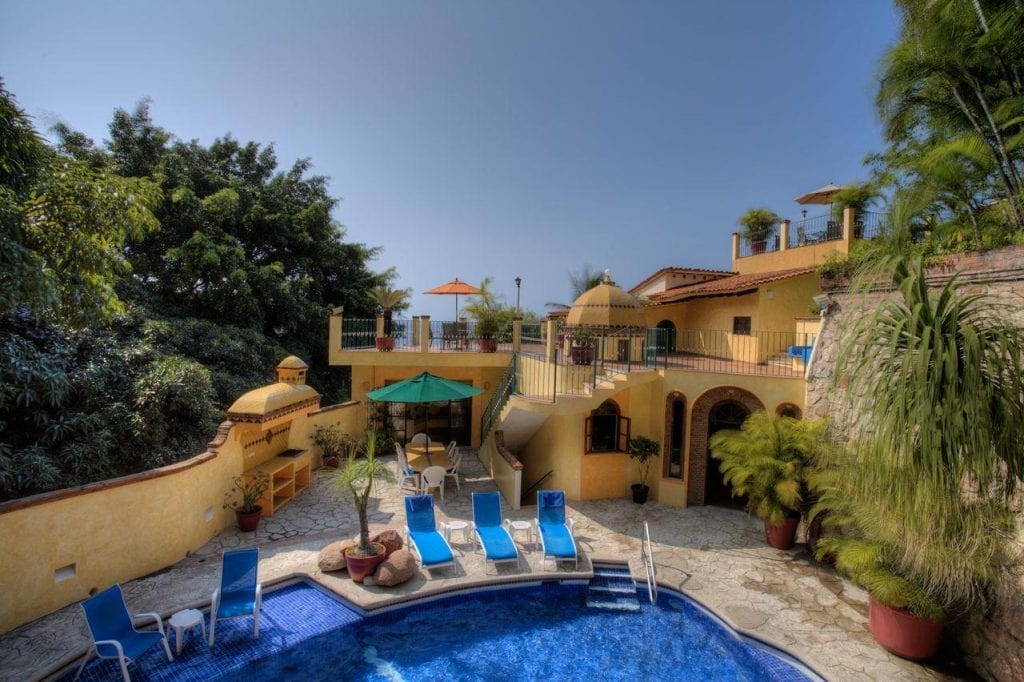 La Villita swimming pool below yellow terraces and trees — Puerto Vallarta, Mexico