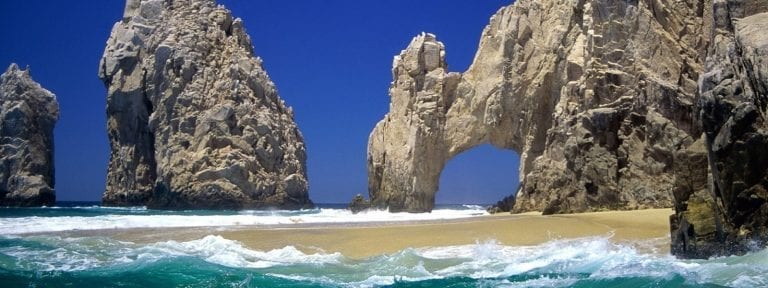 Natural rock arch and sea stacks beside a sandy cove