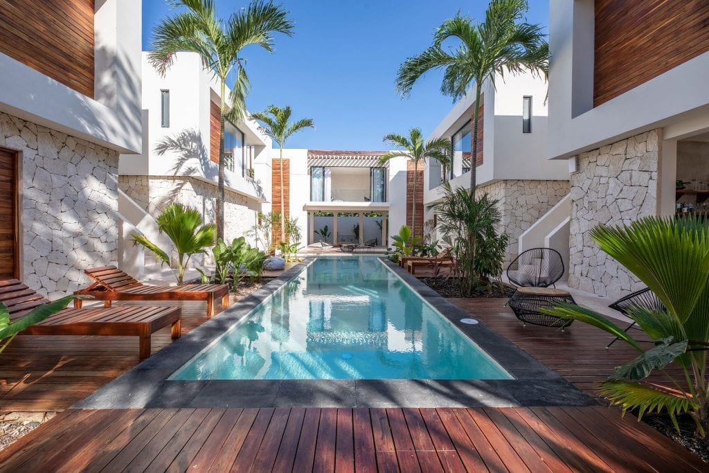 Hacienda 21 courtyard with narrow pool, wood deck and villa buildings — Tulum, Mexico