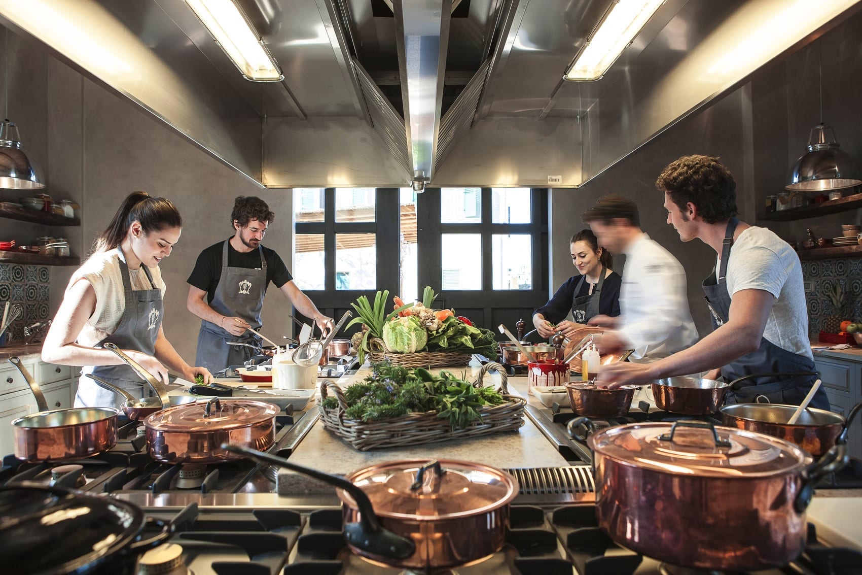 Chefs preparing a meal together in a villa kitchen lined with copper pots — Punta Mita, Mexico