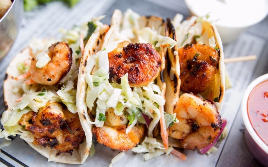 An image of a beautifully plated Tacos de Camarón dish prepared by the chef of Casa Koko in Punta Mita, Mexico, featuring fresh shrimp, vibrant vegetables, and garnished with lime and cilantro.