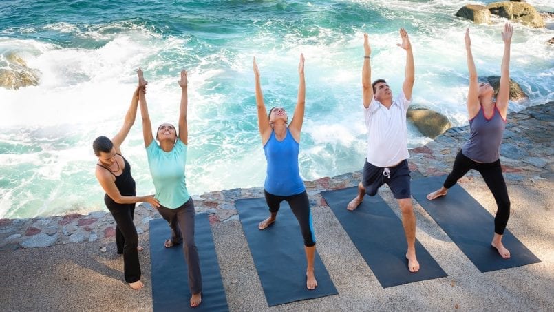 Yoga group practicing on a terrace with ocean views during a wellness retreat in Puerto Vallarta villa.
