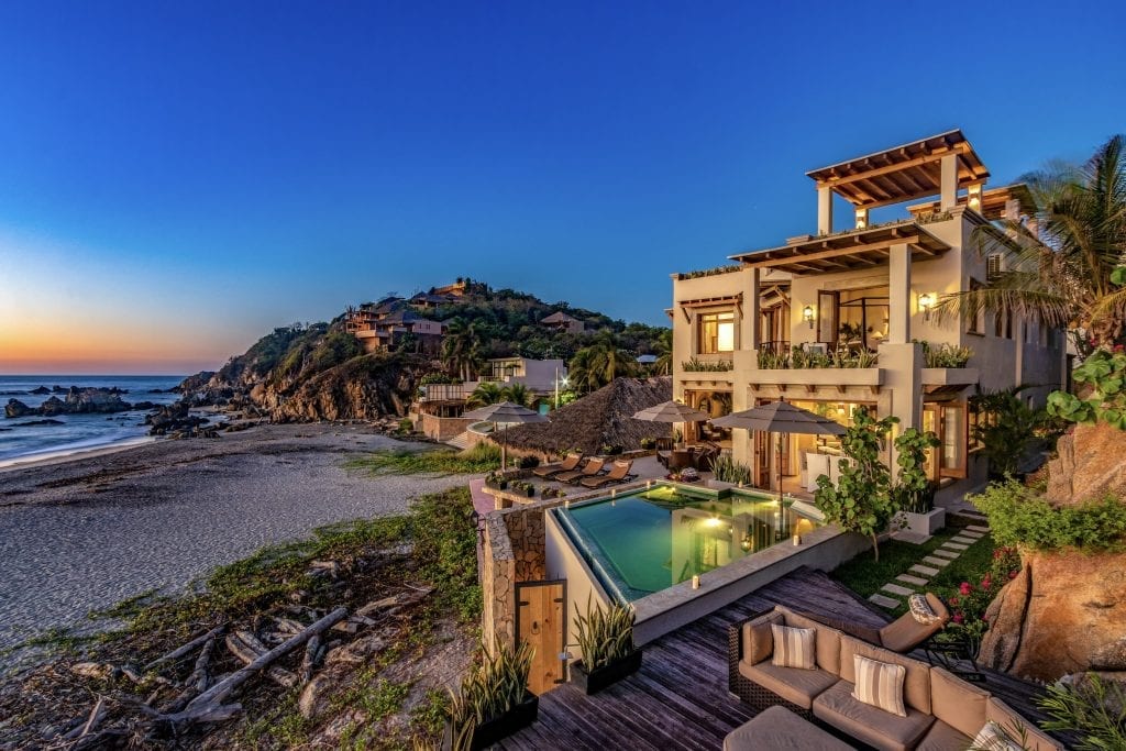 Villa Escondida exterior at dusk with a pool beside the beach — Huatulco, Mexico
