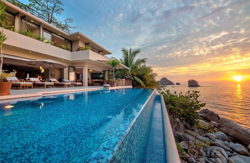 Villa Namaste pool running beside the villa toward offshore rocks at sunset — Puerto Vallarta, Mexico