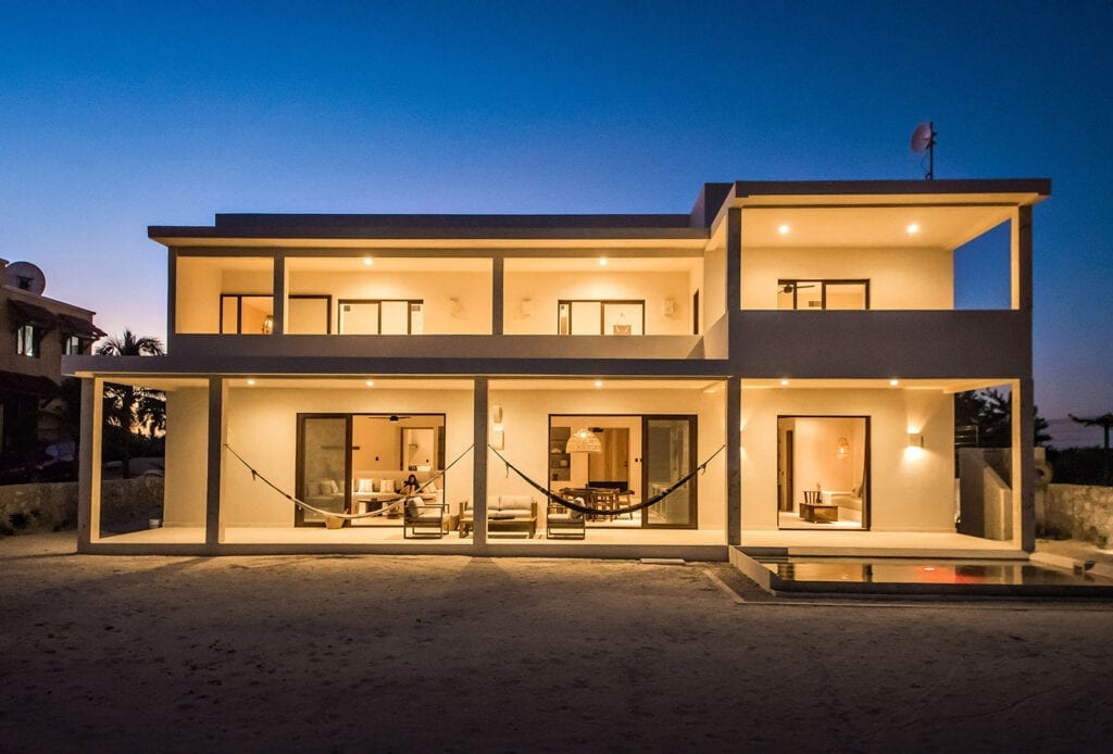 Blanca Beach House illuminated two-story facade with a hammock and pool at dusk — Cancun, Mexico