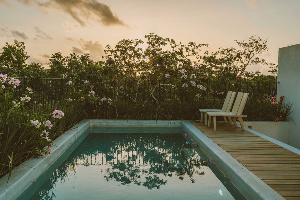 Villa Fosca pool terrace at sunset with two lounge chairs — Tulum, Mexico
