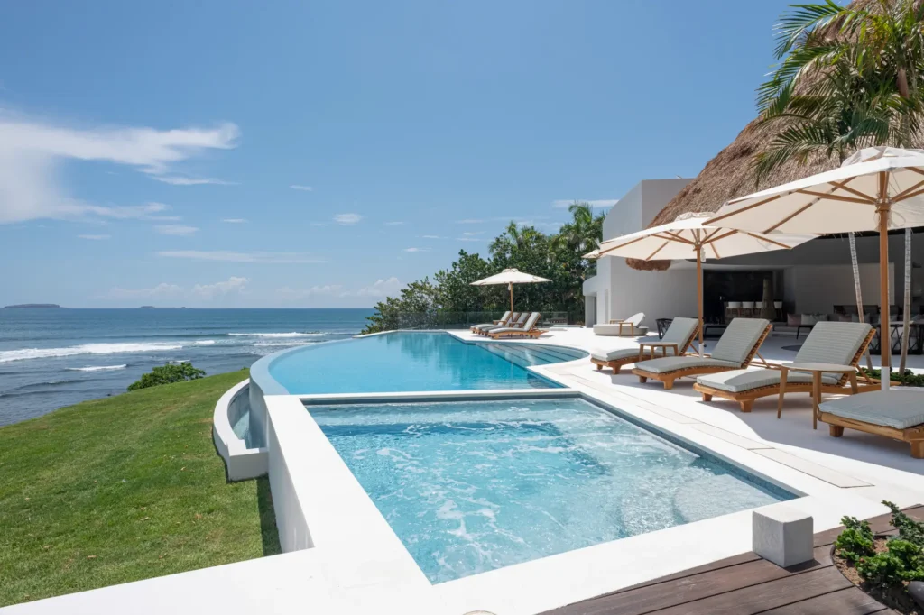 Casa Akai small bubbling pool beside the curved main pool, lawn, and ocean — Punta Mita Nayarit, Mexico