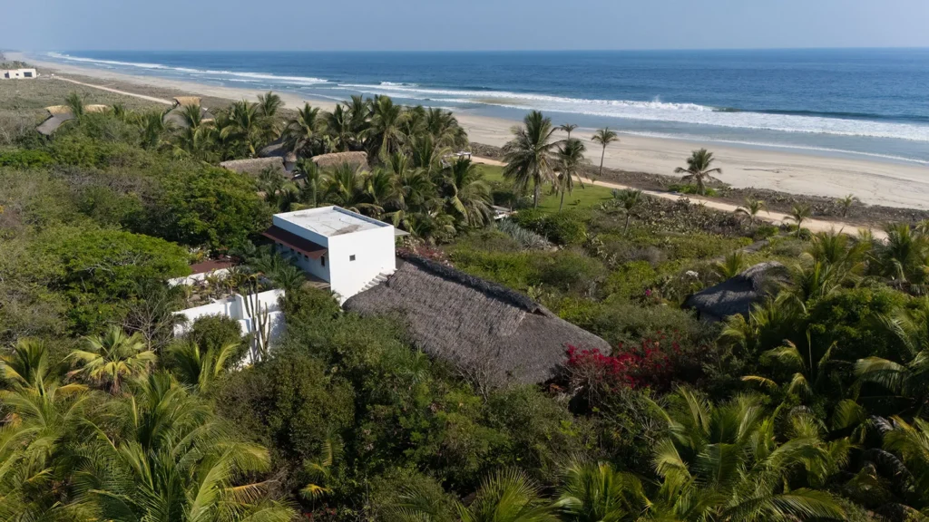 Bungalow Lavanda – Los Guajes aerial view of buildings and palms beside the long beach — Puerto Escondido, Mexico