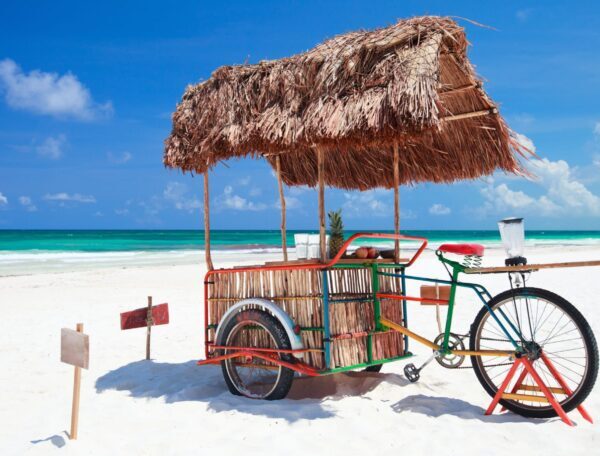 Triciclo con techo de palapa en la playa de la Riviera Maya