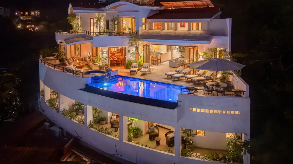 Villa Ventana illuminated multilevel facade and pool against the hillside at night — Puerto Vallarta, Mexico