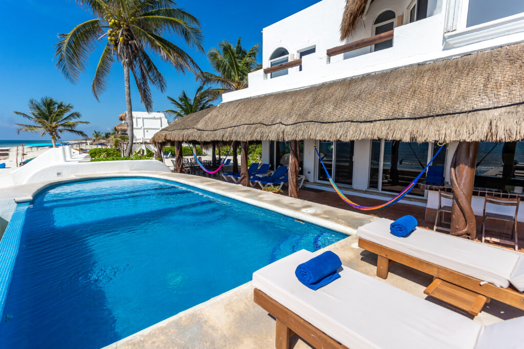 Villa Can Teena beachfront pool with loungers below the thatched villa facade — Playa del Carmen, Mexico