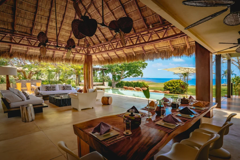Casa Kalika palapa dining table and lounge beside the pool and lawn — Punta Mita Nayarit, Mexico