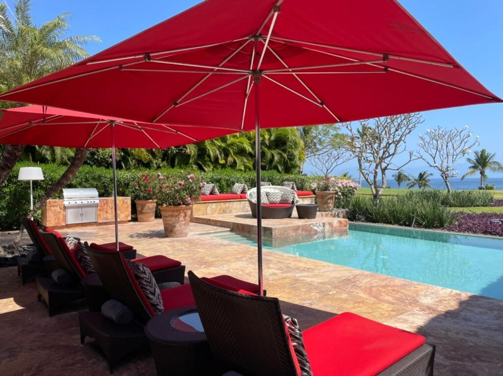 Casa Cavallino pool terrace with a red umbrella, lounge seating and grill — Punta Mita Nayarit, Mexico