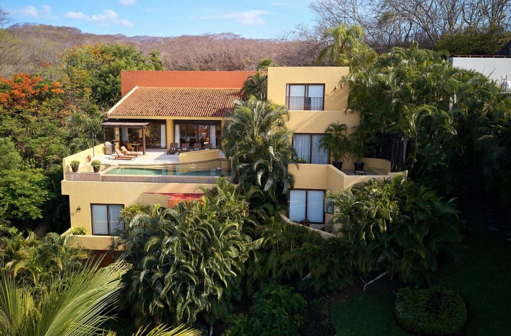 Casa Colores multilevel exterior with a pool terrace, red tiled roof and dense palms — Punta Mita Nayarit, Mexico