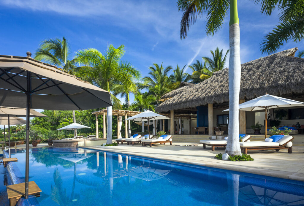 Casa La Caleta long pool lined with loungers and shade umbrellas — Punta Mita Nayarit, Mexico