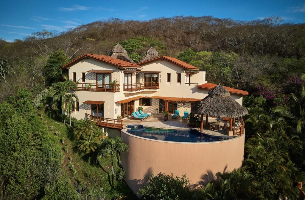 Casa Libelula aerial view of hillside villa with curved pool and thatched palapa — Punta Mita Nayarit, Mexico