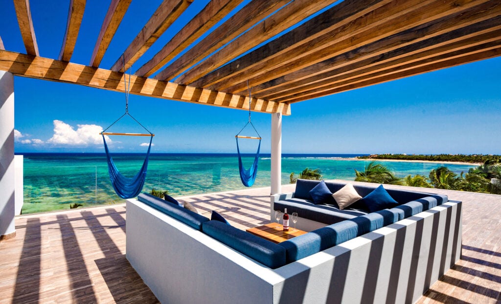 Casa Napa rooftop pergola with blue hanging chairs and a striped daybed — Tulum, Mexico