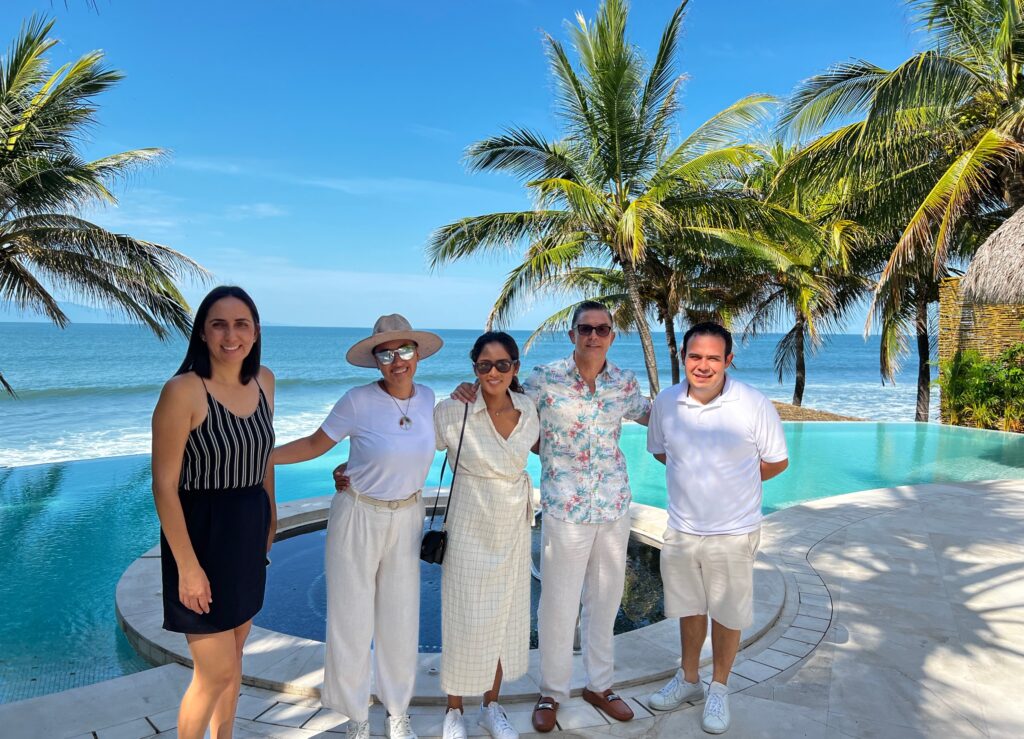 The Villa Experience Team standing in front of the pool of a luxurious villa in Punta de Mita, with the beach in the background.