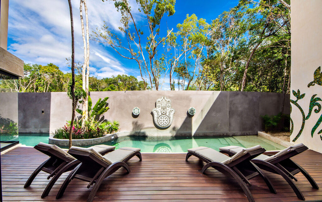 Lounge chairs by the pool with a terrace backdrop at a luxury villa in Aldea Zama, Tulum.