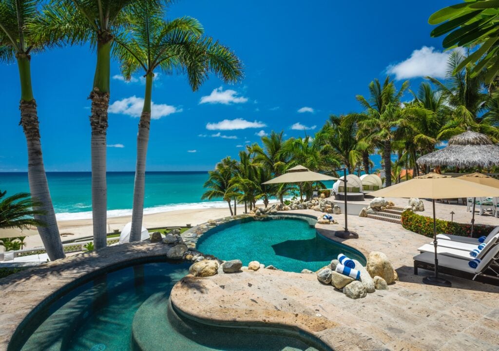 Casa Edwards curving pool with rounded shallow section and loungers above the beach — Los Cabos, Mexico