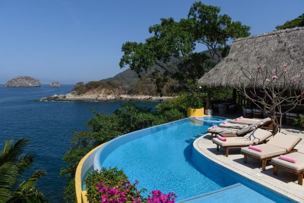 Villa Mandarinas infinity pool with loungers and a palapa above the ocean and islets — Puerto Vallarta, Mexico